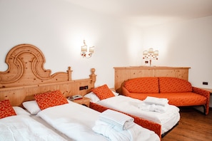Een hotelkamer met twee bedden, elk voorzien van oranje en witte beddengoed, een houten hoofdbord en een nachtkastje met een lamp.