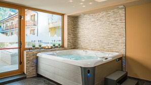 Une salle de bain moderne dotée d’une grande baignoire, d’une porte en verre donnant sur un espace extérieur et d’un mur en pierre.
