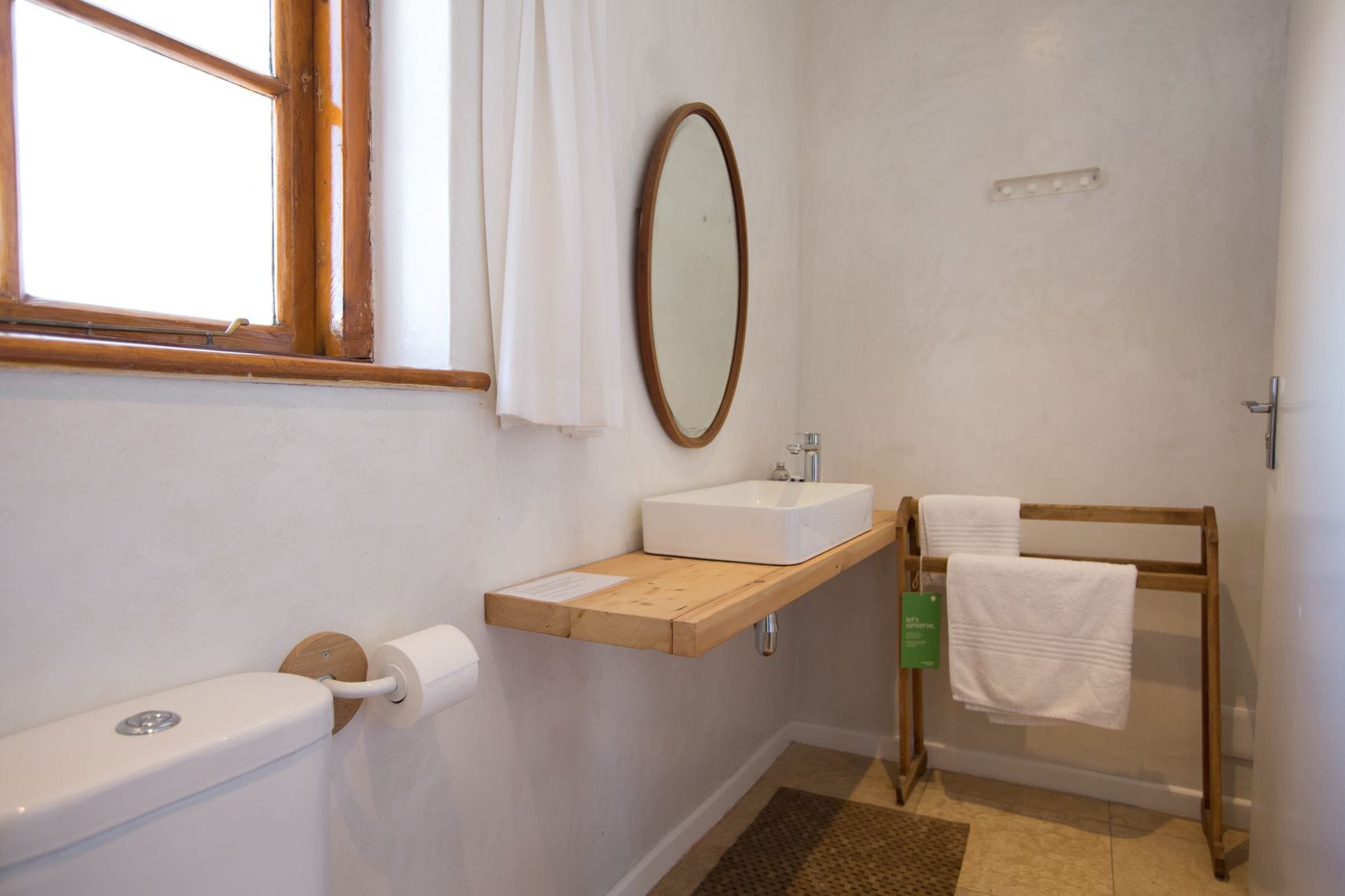 Casa de banho com sanita, lavatório, espelho e porta-toalhas.