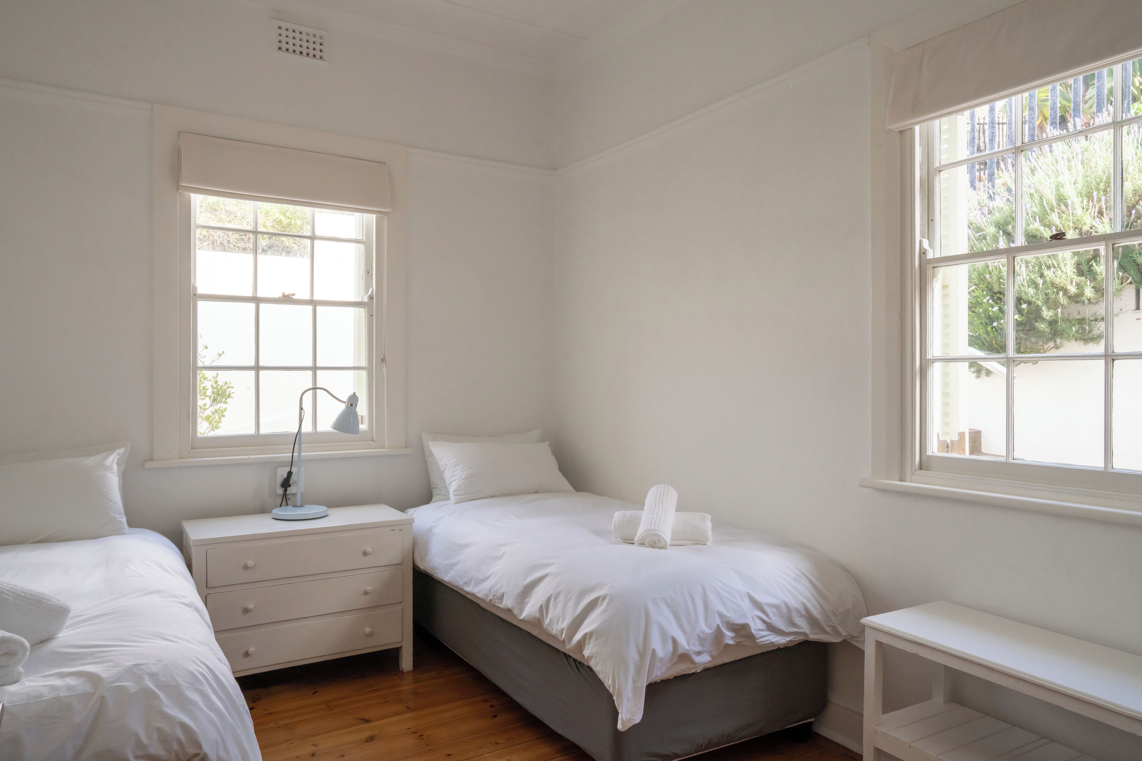 A bedroom with two beds, a nightstand, a dresser, and a window.