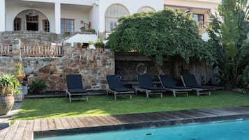 Una piscina al aire libre, sillones reclinables de piscina