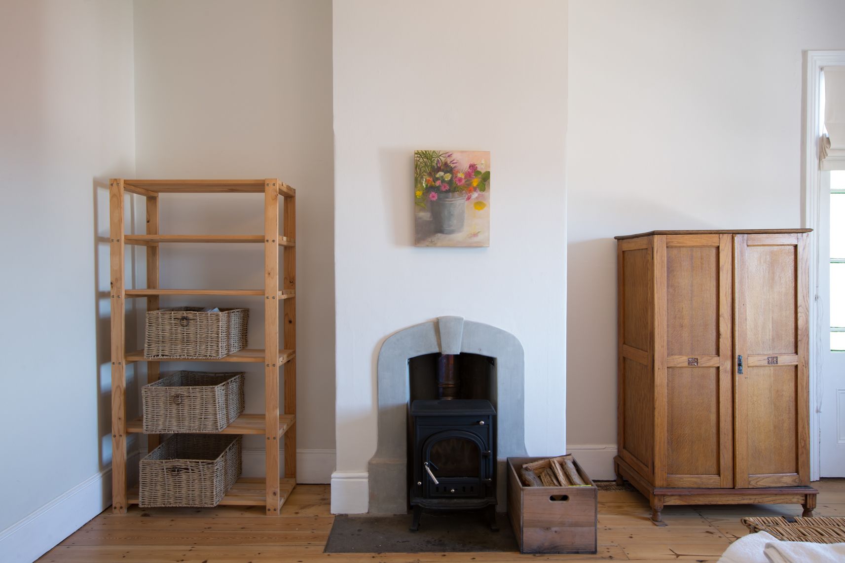 A room with a wooden shelving unit, a fireplace, and a wooden wardrobe.