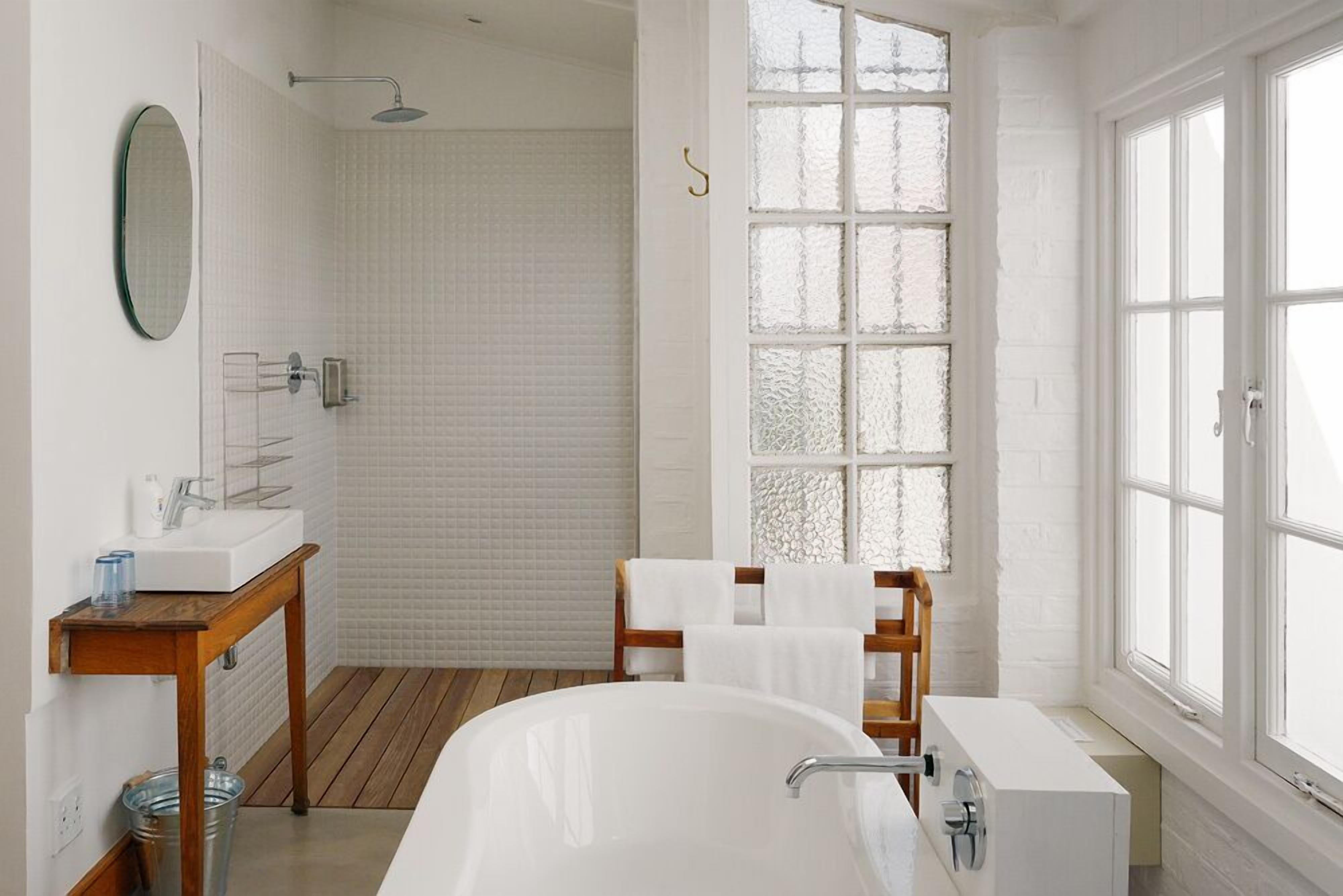 A modern bathroom with a freestanding bathtub, a shower, and a large window.