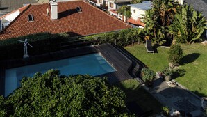 A coastal property with a swimming pool, a view of the sea, and a rocky landscape in the distance.