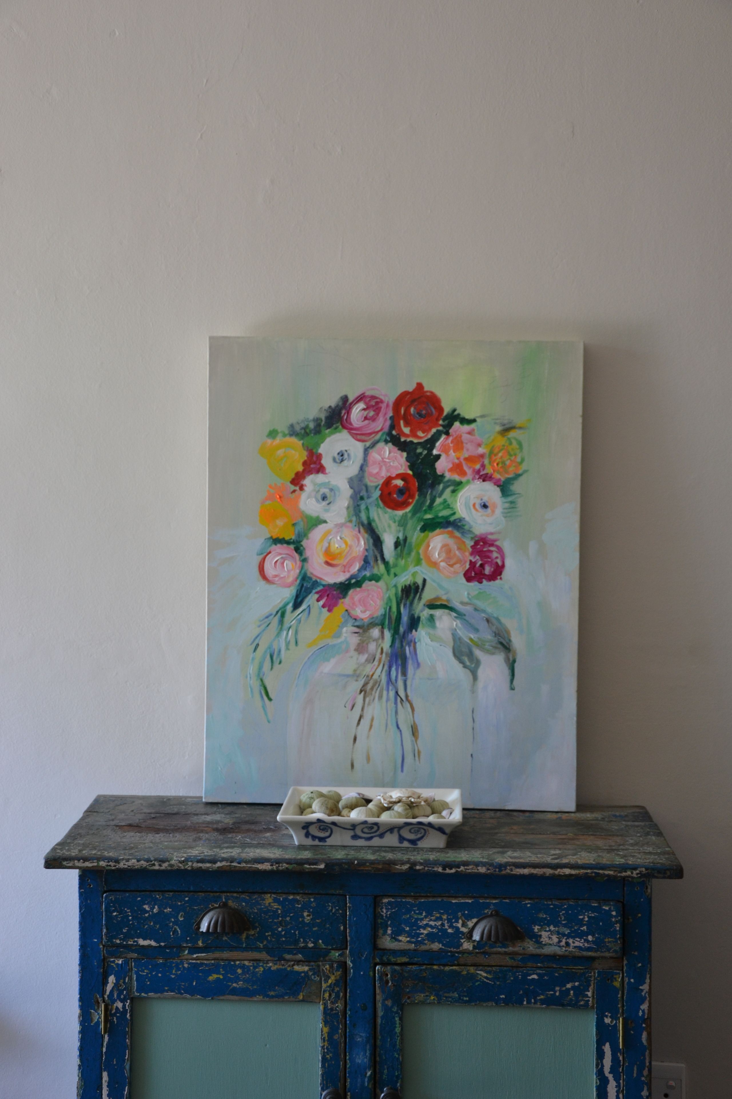 A painting of a bouquet of flowers on a dresser.