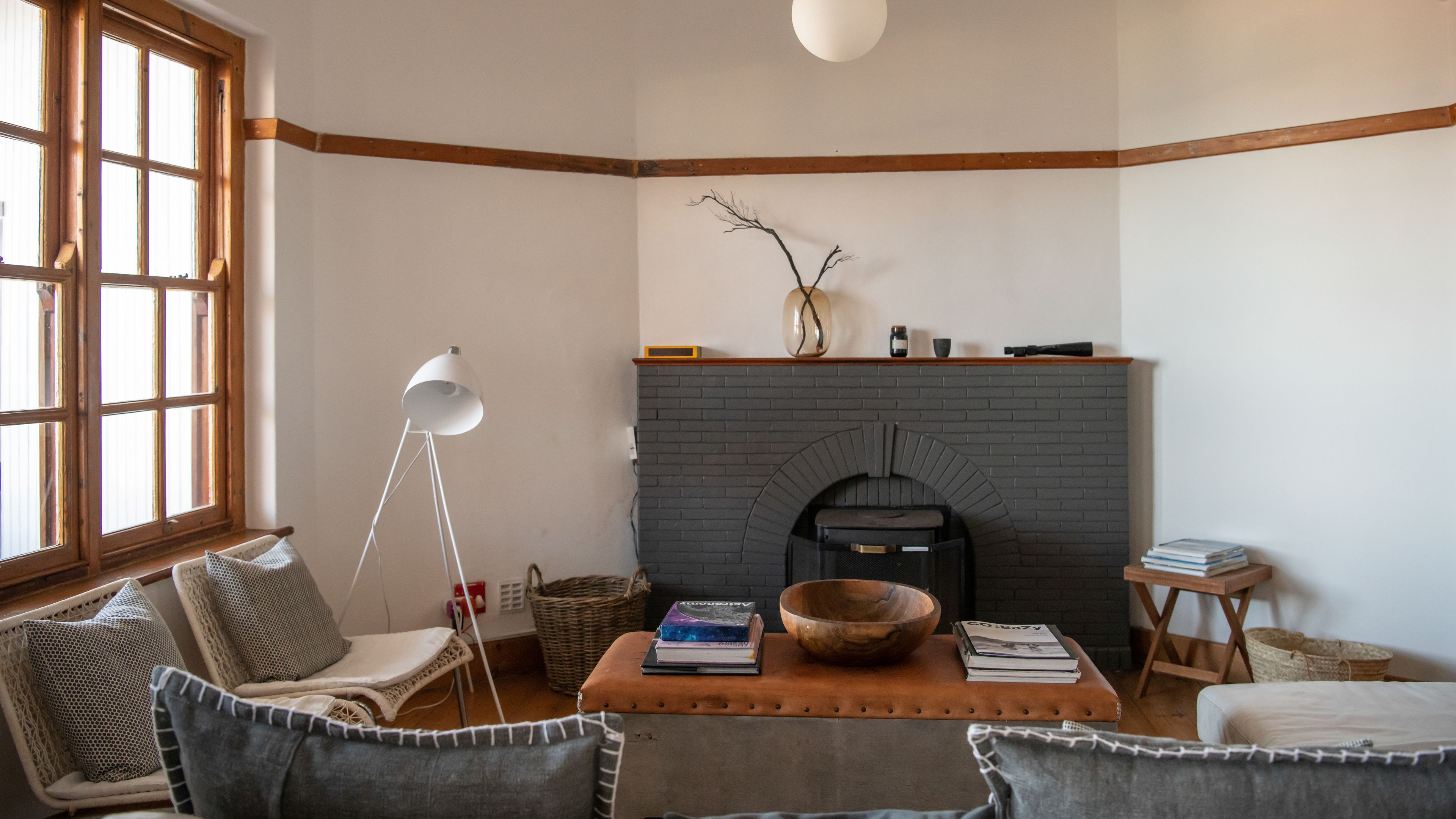A cozy living room with a fireplace, wicker furniture, and books.