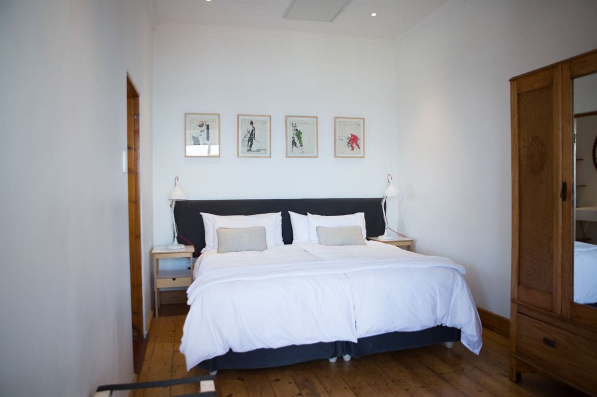 A bedroom with a bed, bedside tables, a wardrobe, and artwork on the wall.