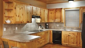 A kitchen with wooden cabinets, a countertop, a sink, a dishwasher, and a window with blinds. - WorldMark New Braunfels (New Braunfels)