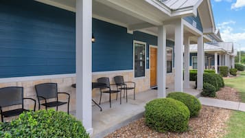 A building with a covered porch, stone walls, and a row of chairs.