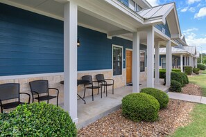 A building with a covered porch, stone walls, and a row of chairs.