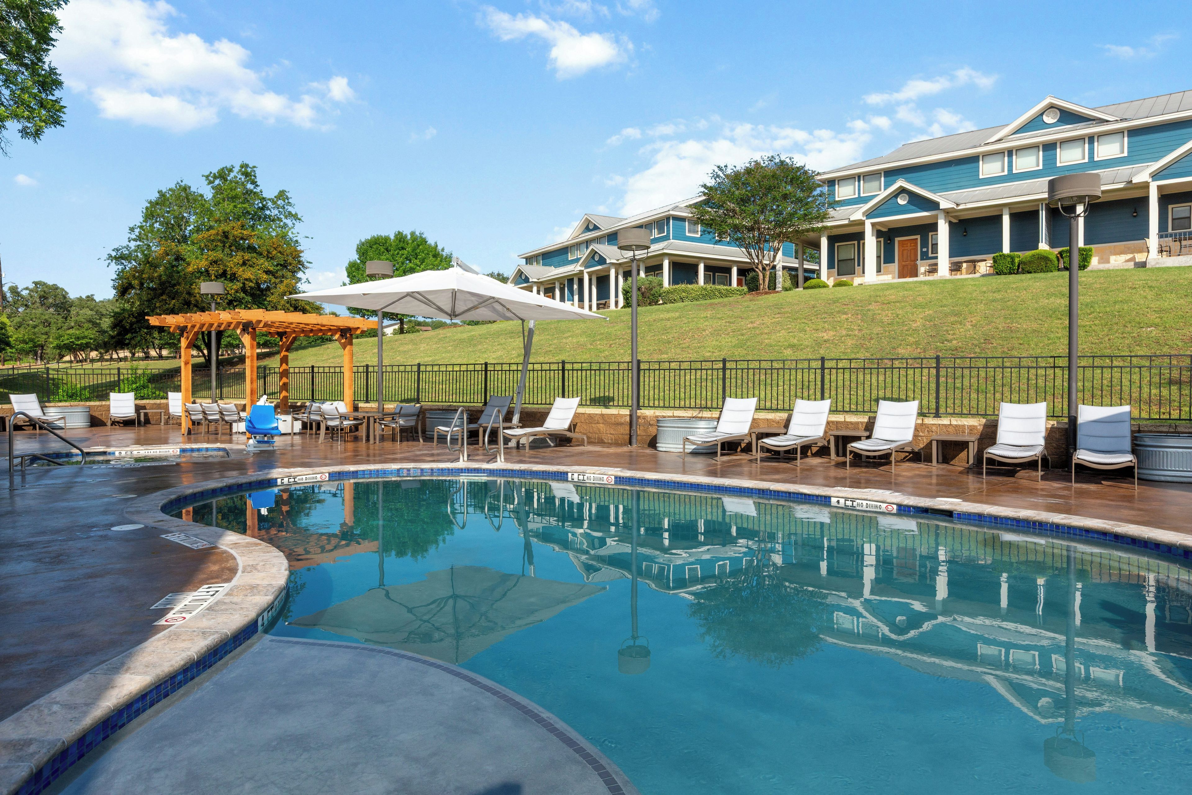 A swimming pool with lounge chairs and a covered seating area.