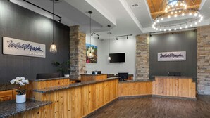 A reception desk with a wooden finish, a flat-screen TV mounted on the wall, and a chandelier with multiple bulbs. - WorldMark New Braunfels (New Braunfels)