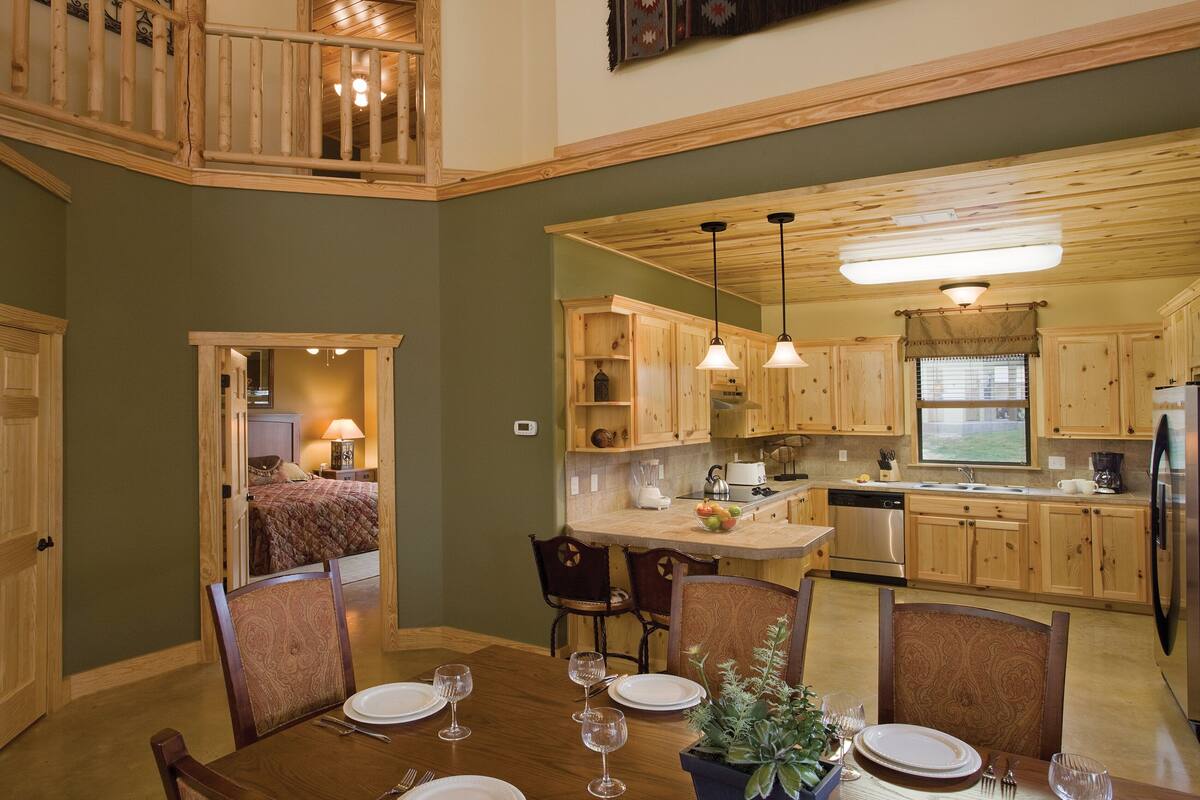 A spacious kitchen with wooden cabinets, a dining area with a high table, and a loft bedroom with a balcony.