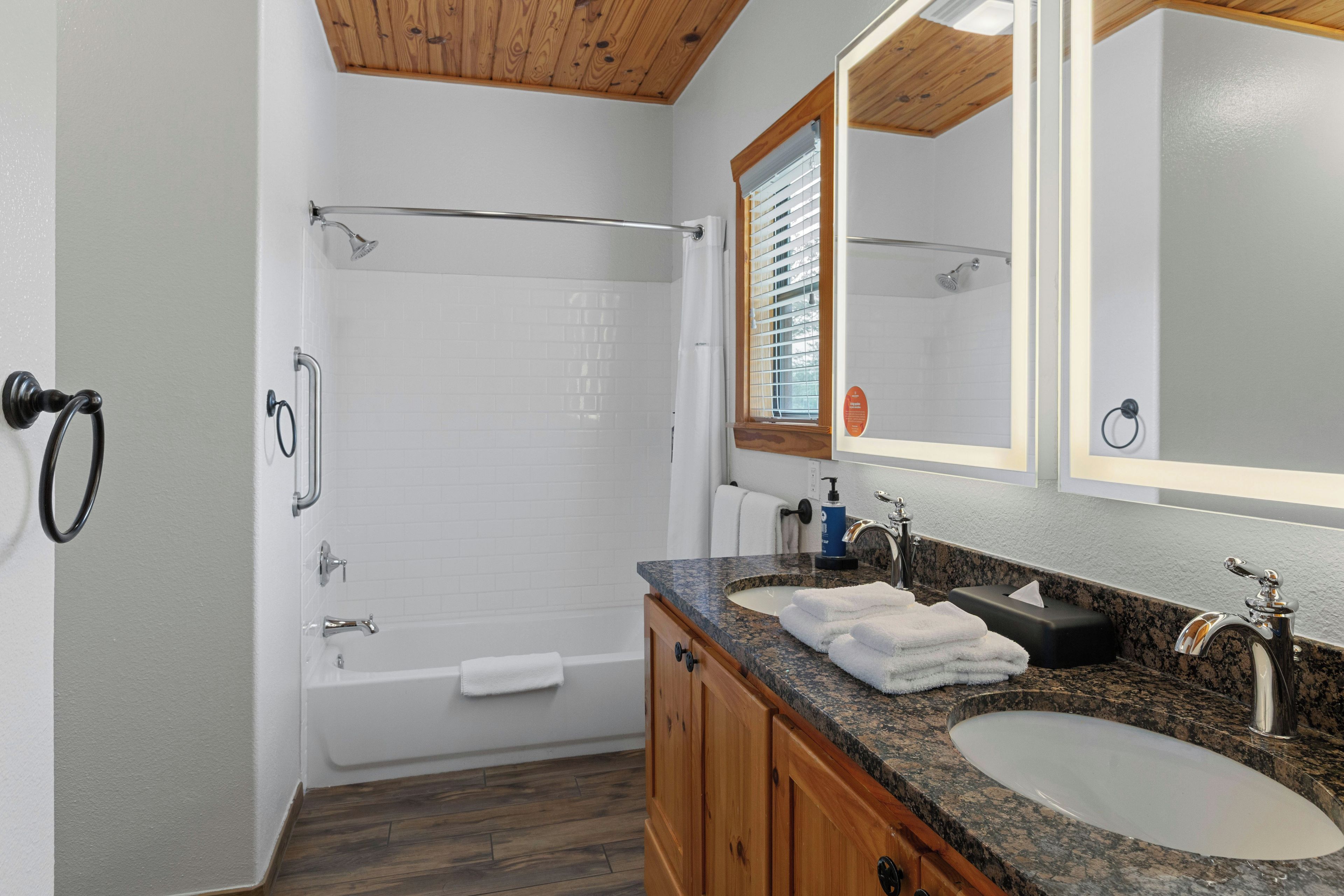 A modern bathroom with a bathtub, a sink, and a large mirror.