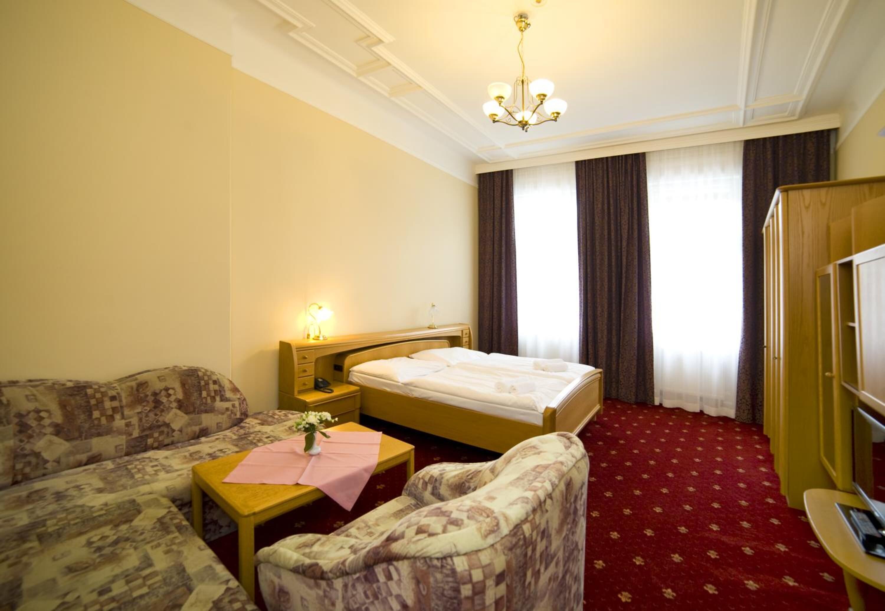 Een hotelkamer met een bed, een bank, een stoel, een bijzettafeltje en een bureau.