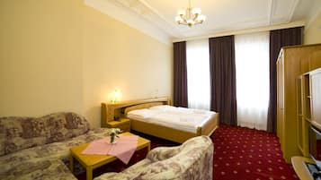 Een hotelkamer met een bed, een bank, een stoel, een bijzettafeltje en een bureau.