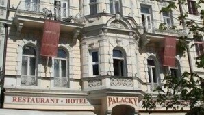 Il s’agit d’un bâtiment historique doté d’une tour centrale, de nombreuses fenêtres et d’enseignes indiquant qu’il abrite un restaurant, un hôtel et un palais.