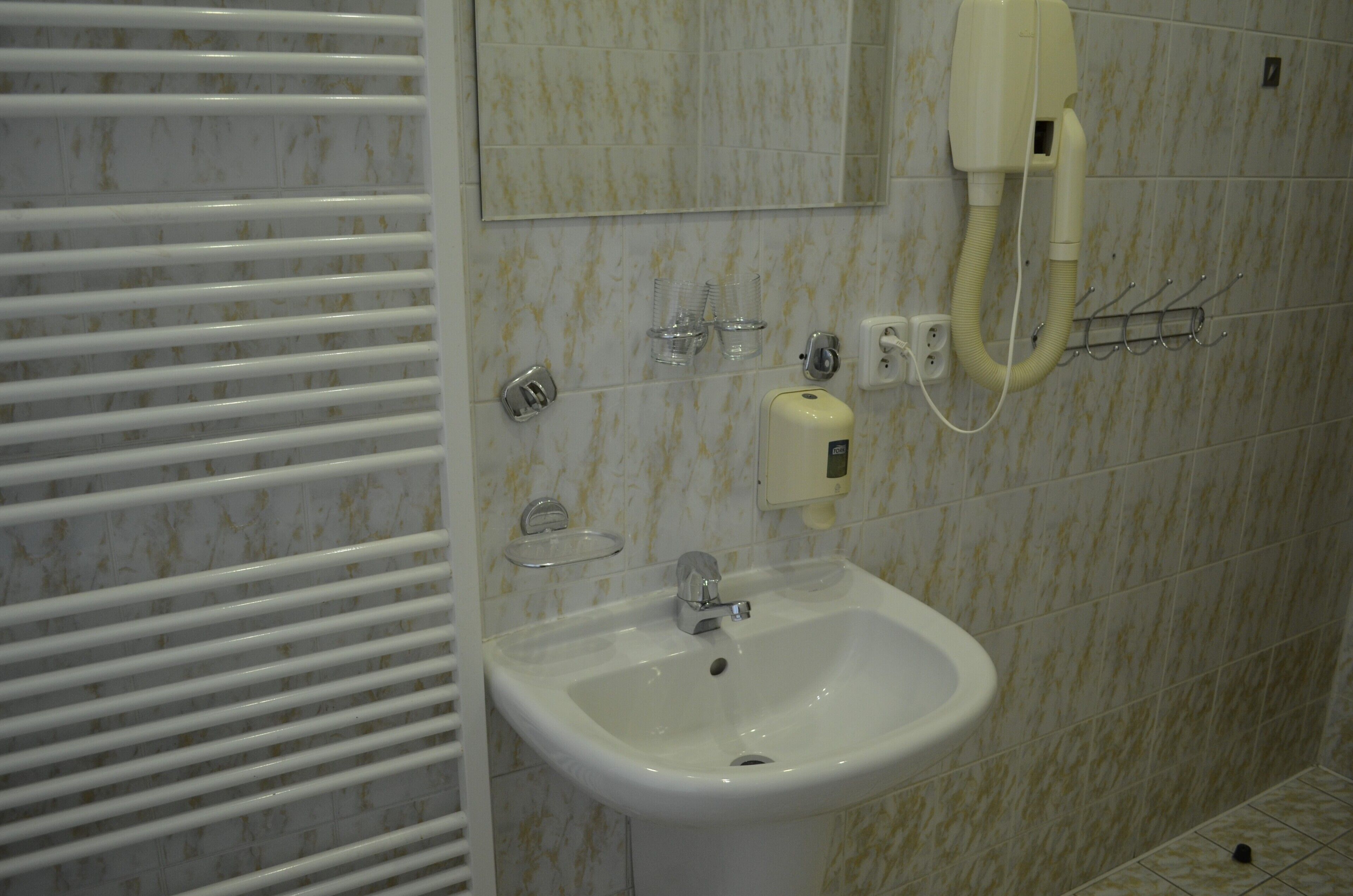 A bathroom with a white sink, a mirror, and a towel rack.