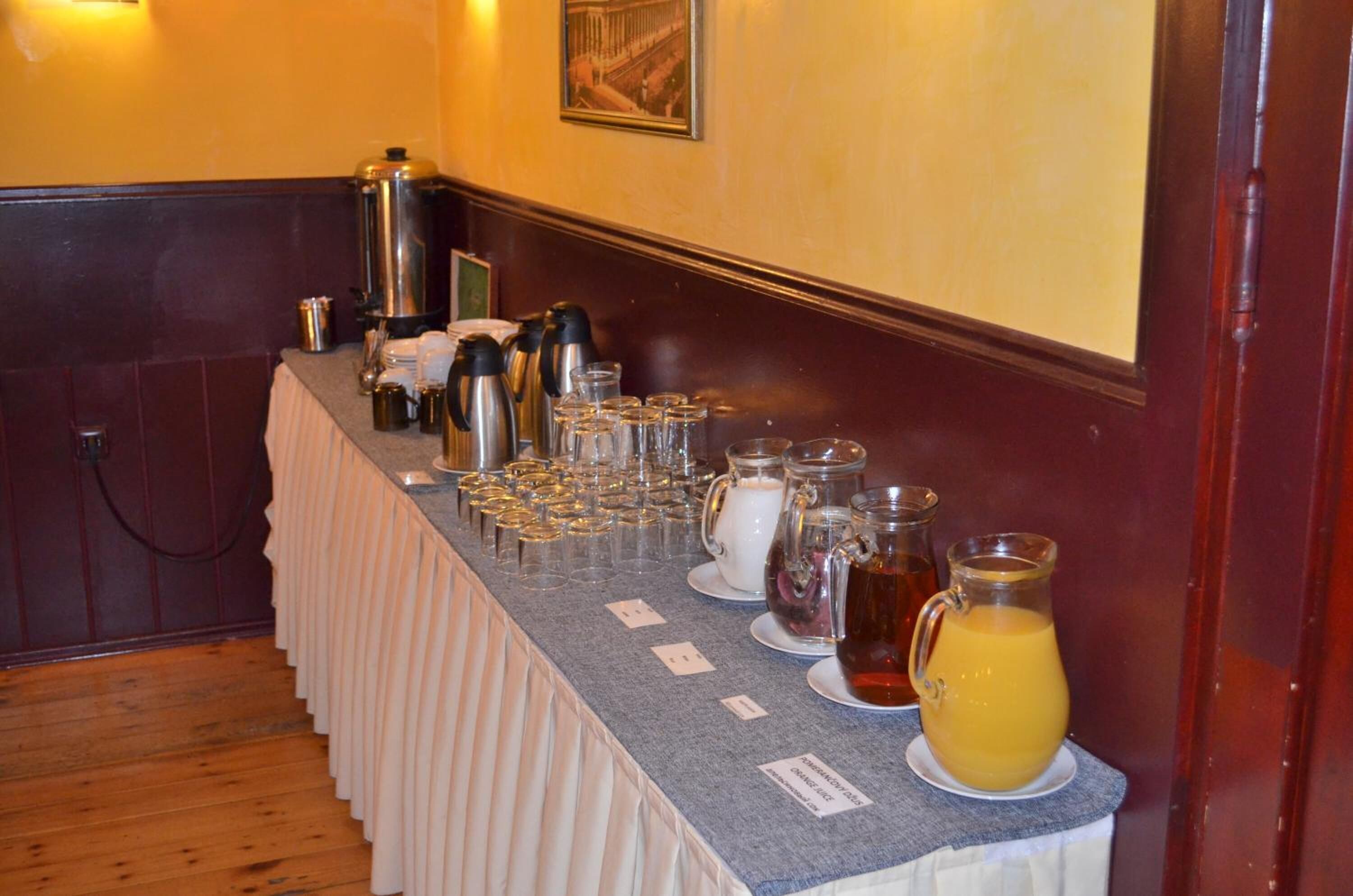 Een buffet met diverse dranken en glazen, een koffiepot en een kan sinaasappelsap.