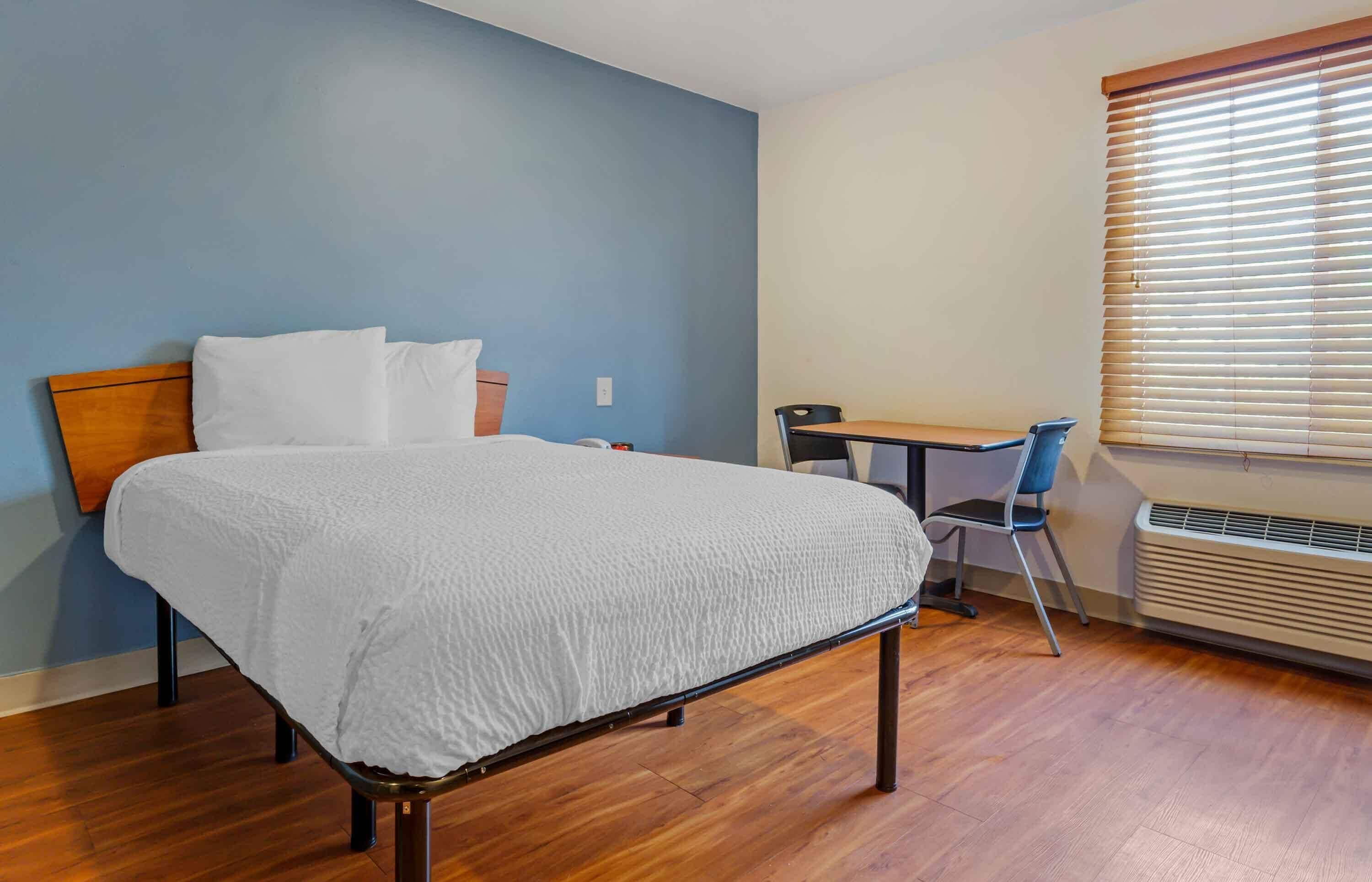 Un dormitorio con cama, escritorio y silla.