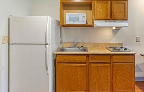 Una cocina compacta con un refrigerador blanco, un microondas, un lavabo y armarios de madera.