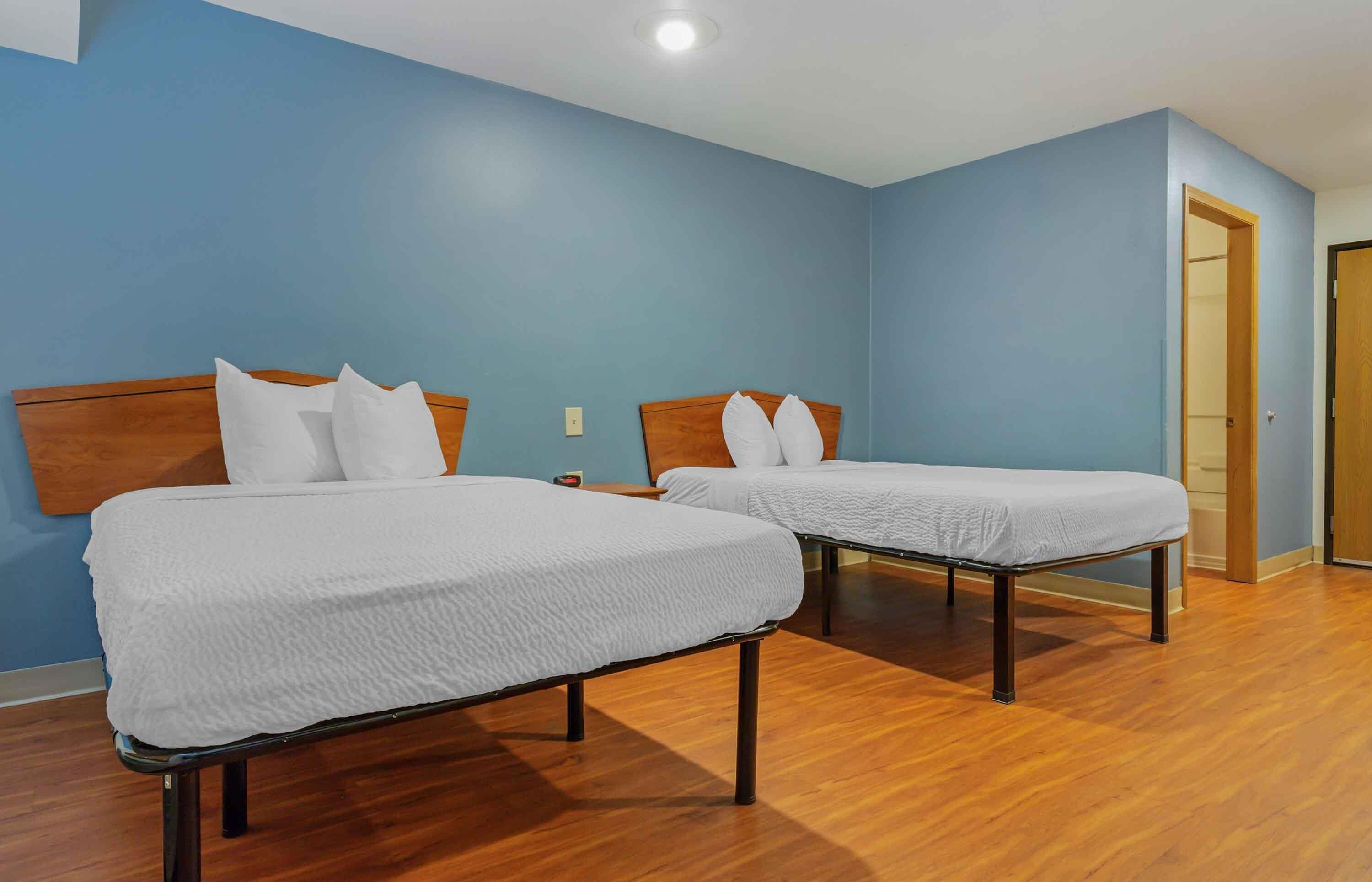 Una habitación con dos camas individuales, cabeceros de madera y suelo de madera.