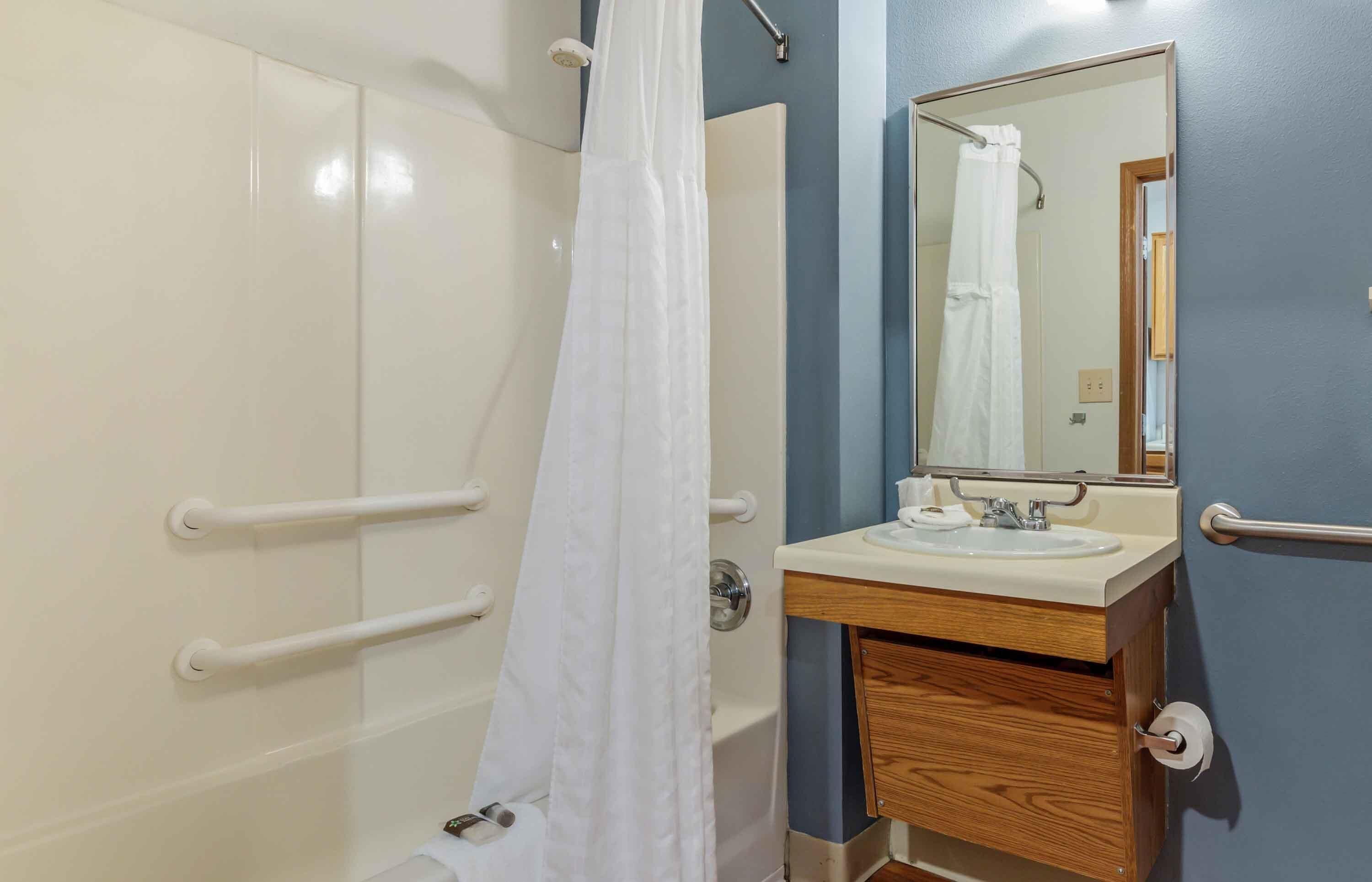 A bathroom with a shower, a sink, and a mirror.