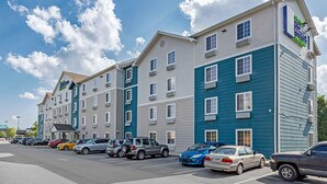 A multi-story hotel with a parking lot in front. - Extended Stay America Select Suites - Fayetteville - West (Fayetteville)