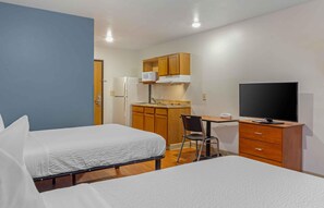 A compact hotel room with two beds, a kitchenette, a desk with a television, and a chair. - Extended Stay America Select Suites - Fayetteville - West (Fayetteville)
