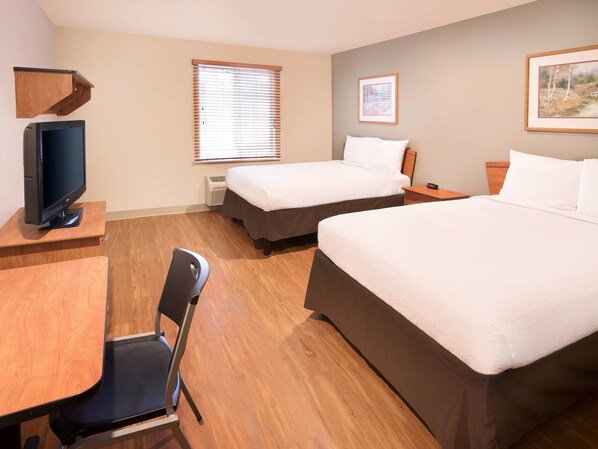 A hotel room with two beds, a desk, a chair, a television, and a window with blinds. - Extended Stay America Select Suites - Fayetteville - West (Fayetteville)