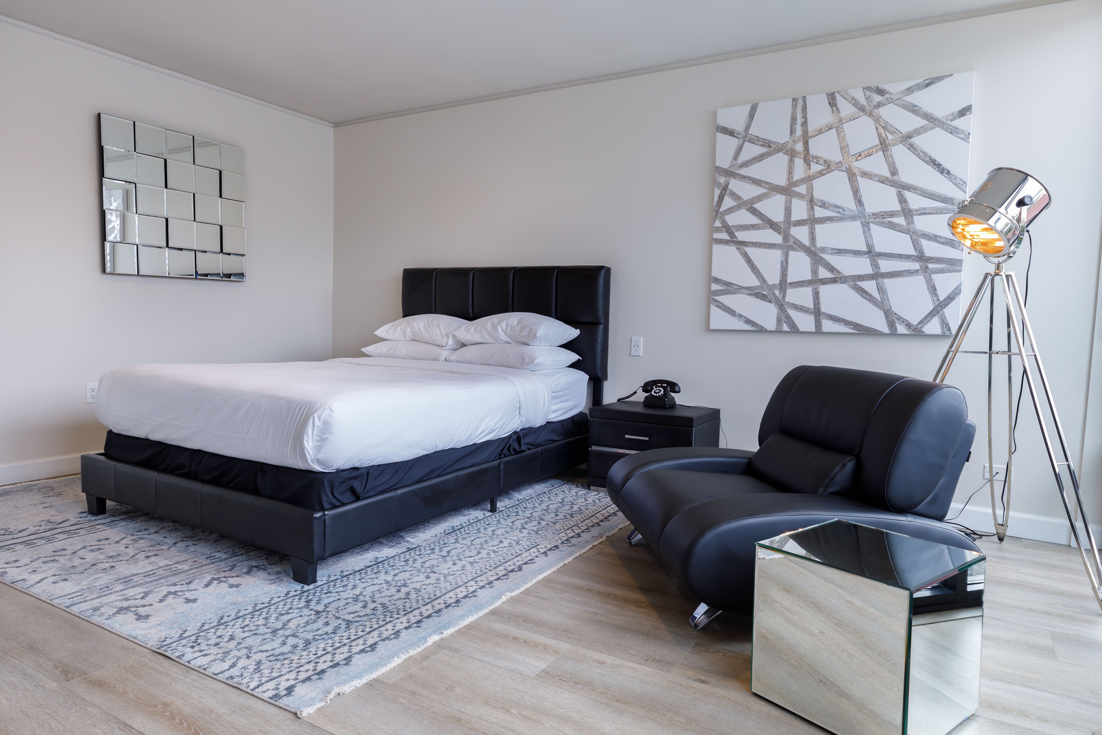 A modern bedroom with a bed, bedside table, lamp, and a chair.