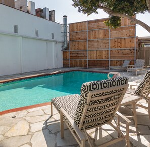 A swimming pool with lounge chairs and a wooden fence.