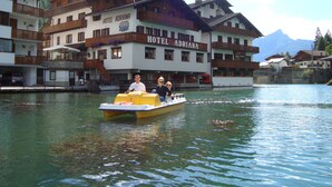 Un bote en un lago, con un hotel llamado "HOTEL ADRIANA" al fondo.