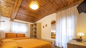 Un dormitorio con techo de madera, una cama con cabecera, una mesita de noche, un espejo y una lámpara.