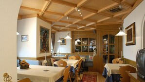 Un comedor con vigas de madera, mesas con manteles blancos y sillas.