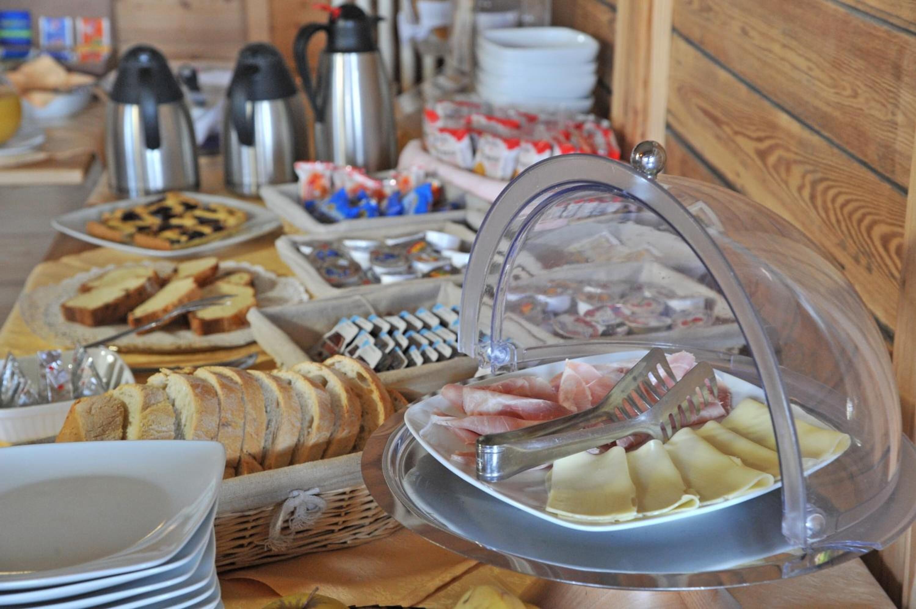Un bufé con diversos alimentos, incluyendo pan, bollería y queso.