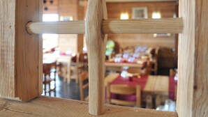 A wooden frame with a view of a dining area, including tables and chairs. - Hotel Maisonnette (Torgnon)