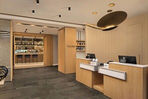 A hotel reception area with a bar, wooden reception desks, and a modern ceiling design. - Courtyard by Marriott Downtown Sibiu (Sibiu)