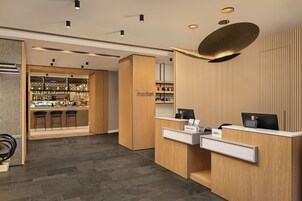 Zona de recepción de un hotel con barra, mostradores de madera y un diseño de techo moderno.