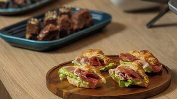 A variety of food items on a wooden table, including sandwiches and pastries.
