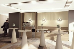 A modern interior with round tables, a water dispenser, and a seating area with a wooden backdrop. - Courtyard by Marriott Downtown Sibiu (Sibiu)