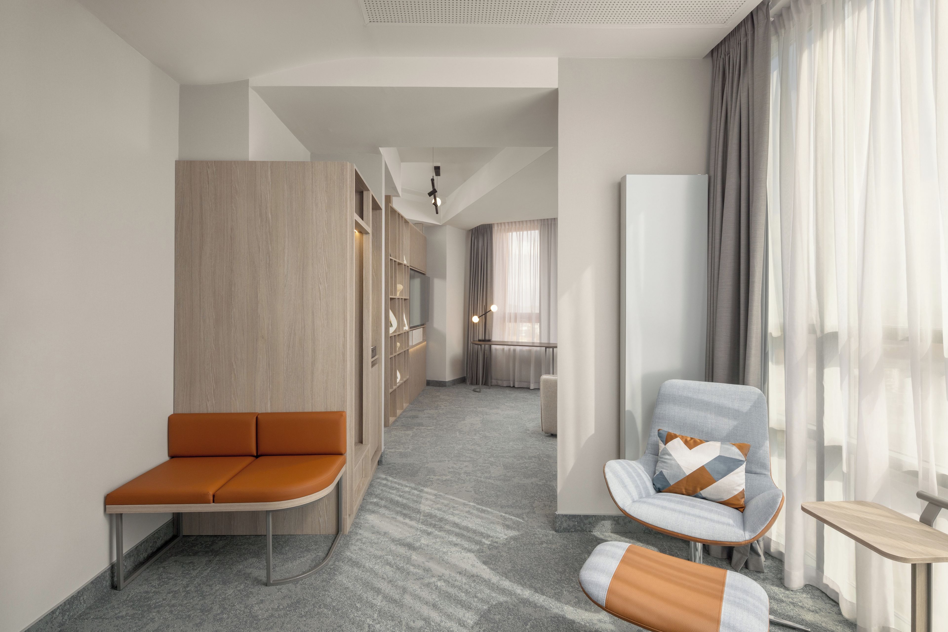 Una habitación de hotel moderna con una zona de estar, un sofá, una silla y una mesita.