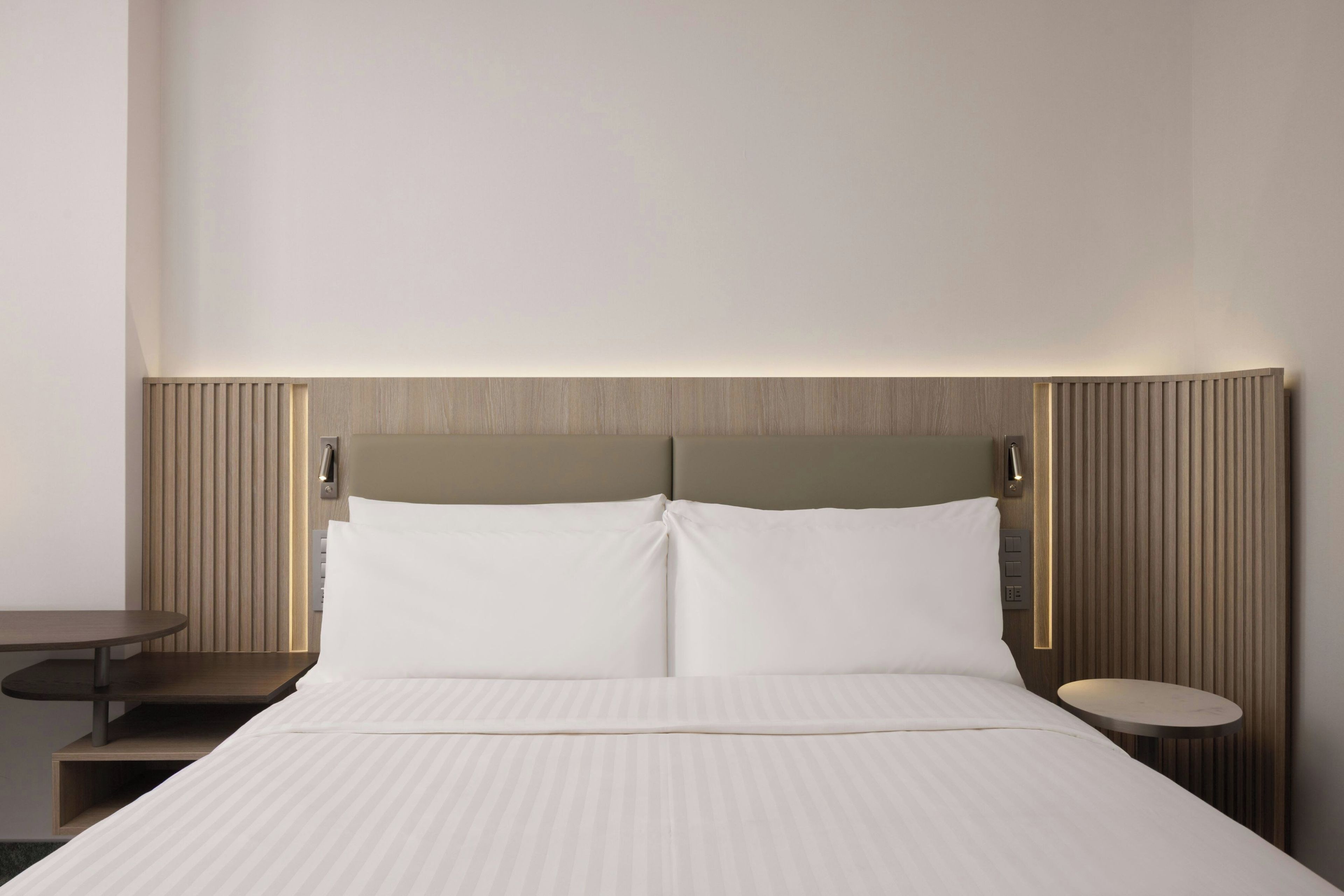 Habitación de hotel con cama, mesitas de noche y una lámpara fijada a la pared.