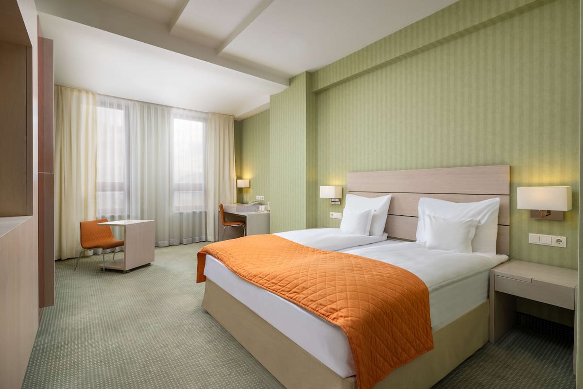 Une chambre d’hôtel avec un grand lit, un bureau et une chaise.
