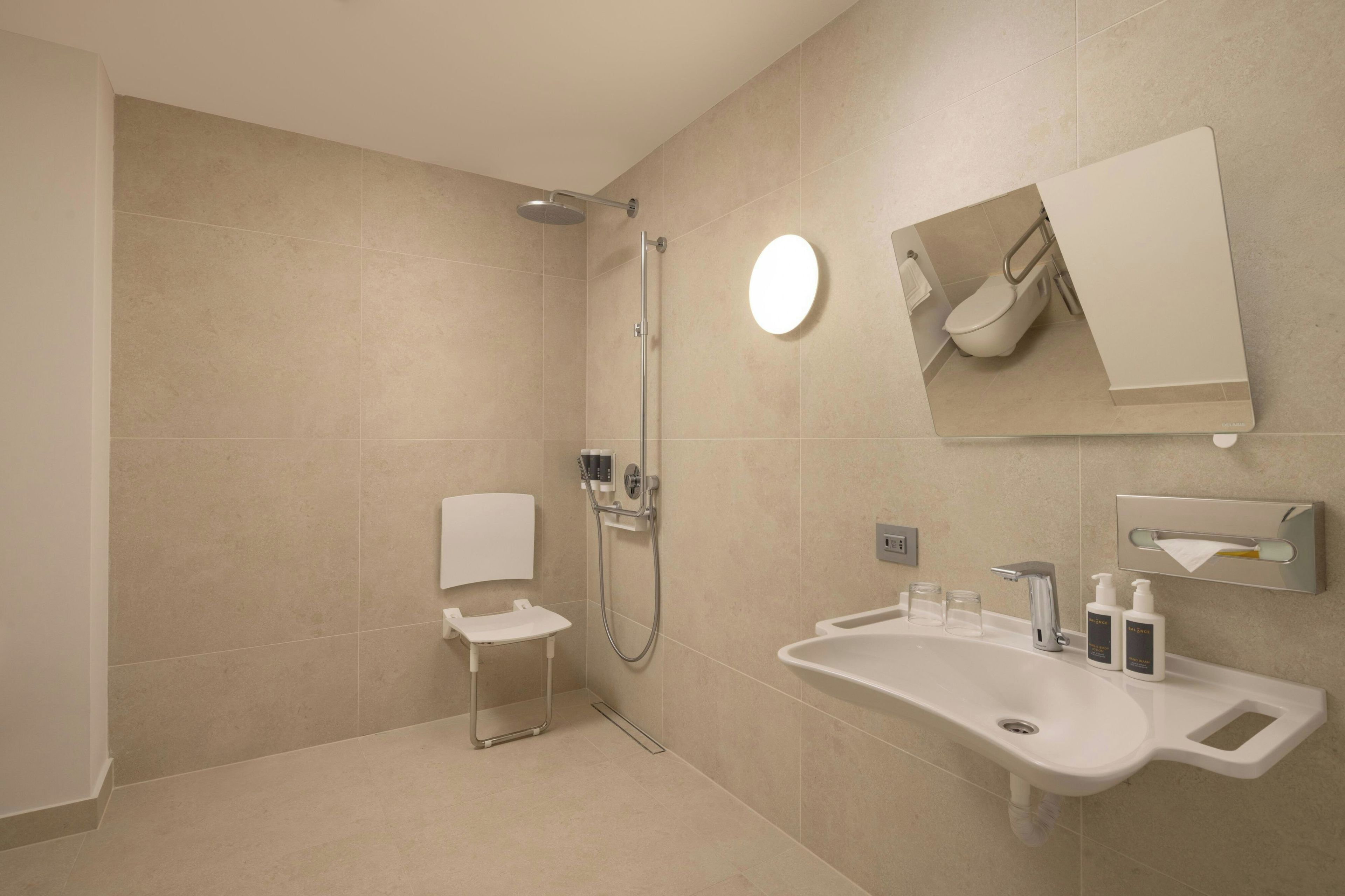 A modern bathroom with a shower, toilet, and sink.