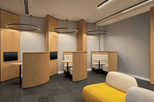 A modern interior with wooden partitions, round tables, and a yellow sofa.