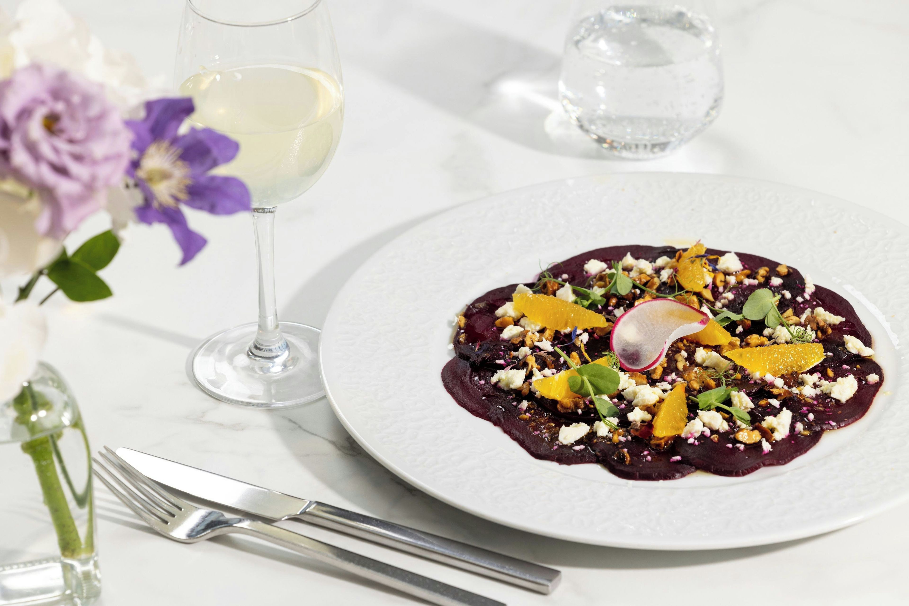 A plate of food with a glass of white wine and a glass of water on a table.