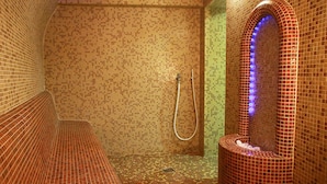 A tiled bathroom with a shower, a bench, and a mirror with a blue light. - Courtyard by Marriott Downtown Sibiu (Sibiu)