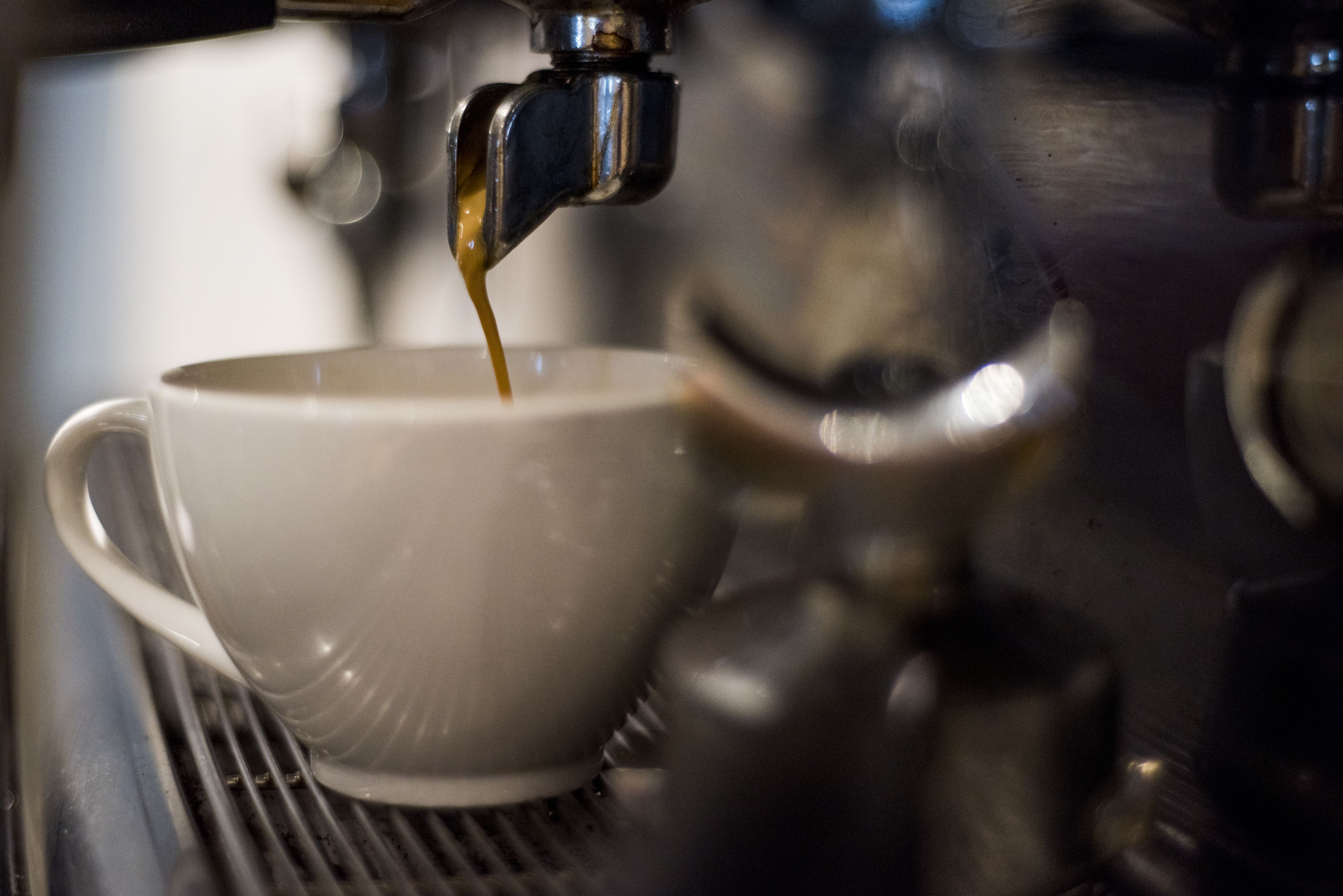Una taza siendo llenada con un líquido, probablemente café, desde una máquina.