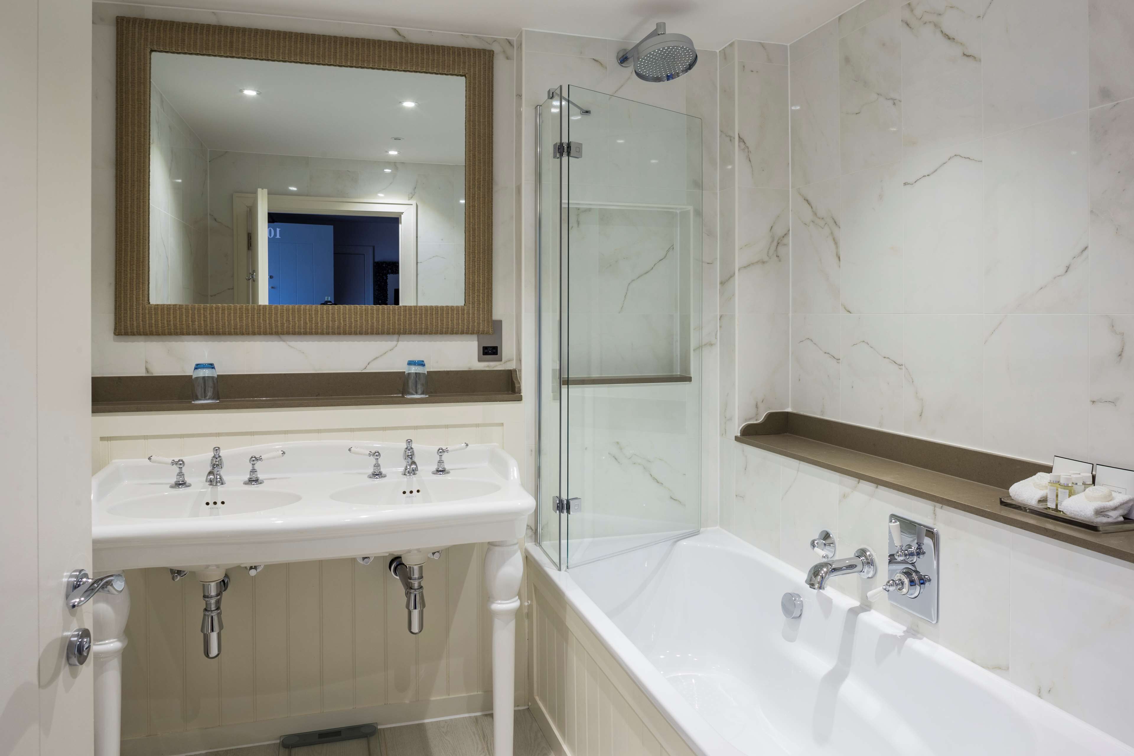 Une salle de bain avec un double lavabo, un grand miroir, une douche à parois de verre et une baignoire.